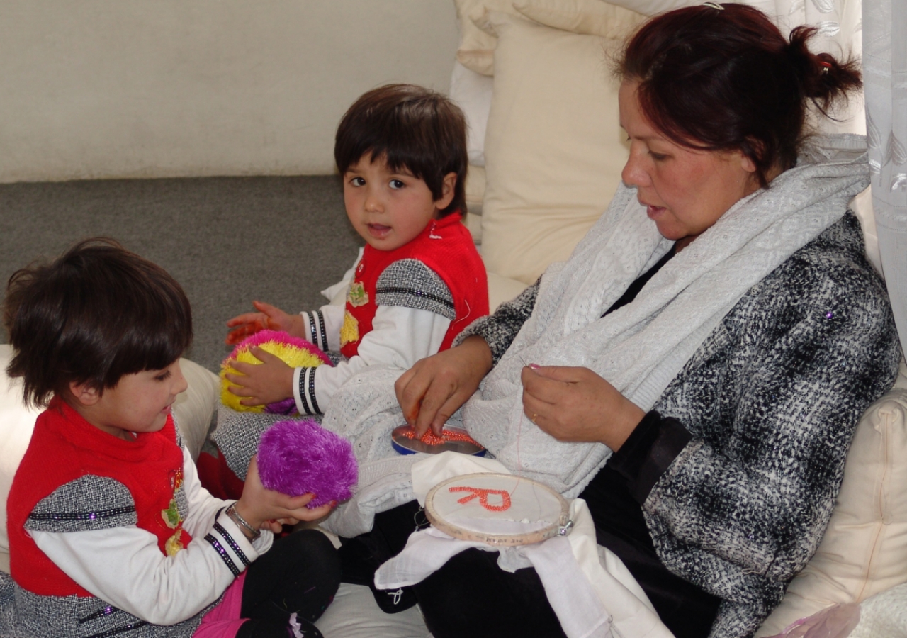 A mother together with her two children, as she helps construct literacy resources for students.