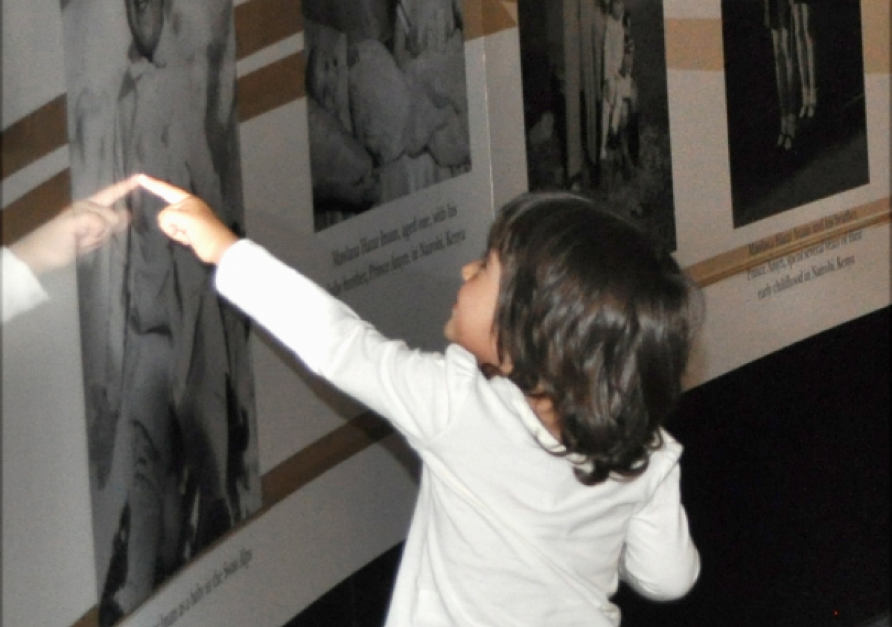 A young visitor delights in a photograph of Mawlana Hazar Imam as a baby.