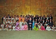 Mawlana Hazar Imam sits for a photograph with performers from the Portuguese Jamat at the conclusion of the Jamati institutional dinner. 