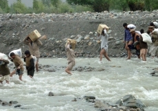 Local volunteers are seen crossing the raging river to make relief goods available to the flood affected communities in Darkut.