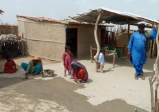 Women in Khidari Bheel, Sind mud-plastering the courtyard floor outside shelters built for them by the Aga Khan Planning and Building Service, Pakistan.