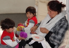 A mother together with her two children, as she helps construct literacy resources for students.