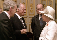 Mawlana Hazar Imam being invested "Knight Commander of the British Empire" (KBE) by Queen Elizabeth II on 5 April 2004. Duke Edinburgh is overlooking.