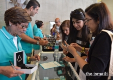 Jamati members peruse tasbihs at the memorabilia desk, served by volunteers.