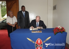 Mawlana Hazar Imam signs the guest book at the State House in Nairobi as His Excellency President Uhuru Kenyatta and First Lady Margaret Kenyatta look on.