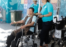 Elderly Jamati members are assisted by volunteers on wheelchair duty.