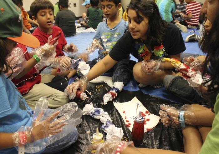 A counselor helps participants tie-die shirts during a self-expression activity at an Ismaili summer camp.