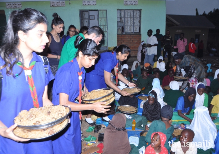 Young members of the Aga Khan Scouts and Guides in Uganda serve meals to orphaned children at the Kasanagati Orphan Fans Society in Kawanda.