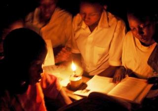 In the absence of electricity, students in a primary school classroom have to study using kerosene lamps.