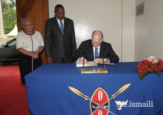 Mawlana Hazar Imam signs the guest book at the State House in Nairobi as His Excellency President Uhuru Kenyatta and First Lady Margaret Kenyatta look on.