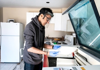 Rahim Bhimani uses the industrial laser cutting machine in his basement to create thousands of face shields for healthcare workers. 