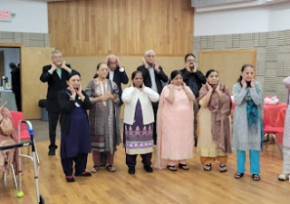 Seniors at Atlanta Northwest Jamatkhana doing face yoga.