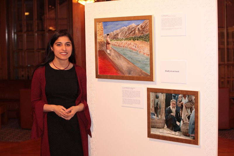 Amynah Goawalla stands beside her work, “Historic Reunion” (top), which depicts the epic moment when Mawlana Hazar Imam addressed the Jamat in Afghanistan from across the river in Tajikistan. The photograph below, “Man Selling His Produce in Kashgar Market,” was taken by Karim Jivraj. Photo: Courtesy of the Ismaili Council for the UK