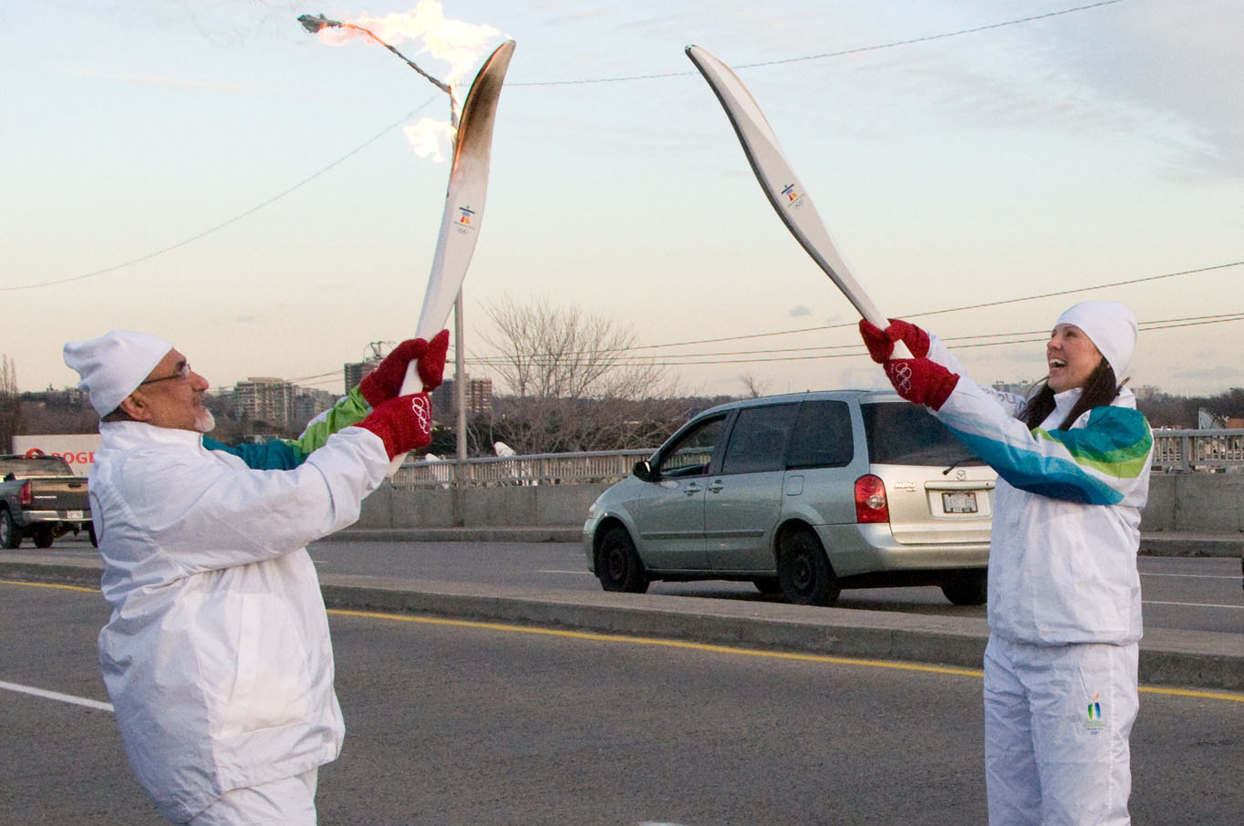 At the end of his run, President Manji passes the Olympic flame to the next runner by lighting her torch. Photo: Moez Visram