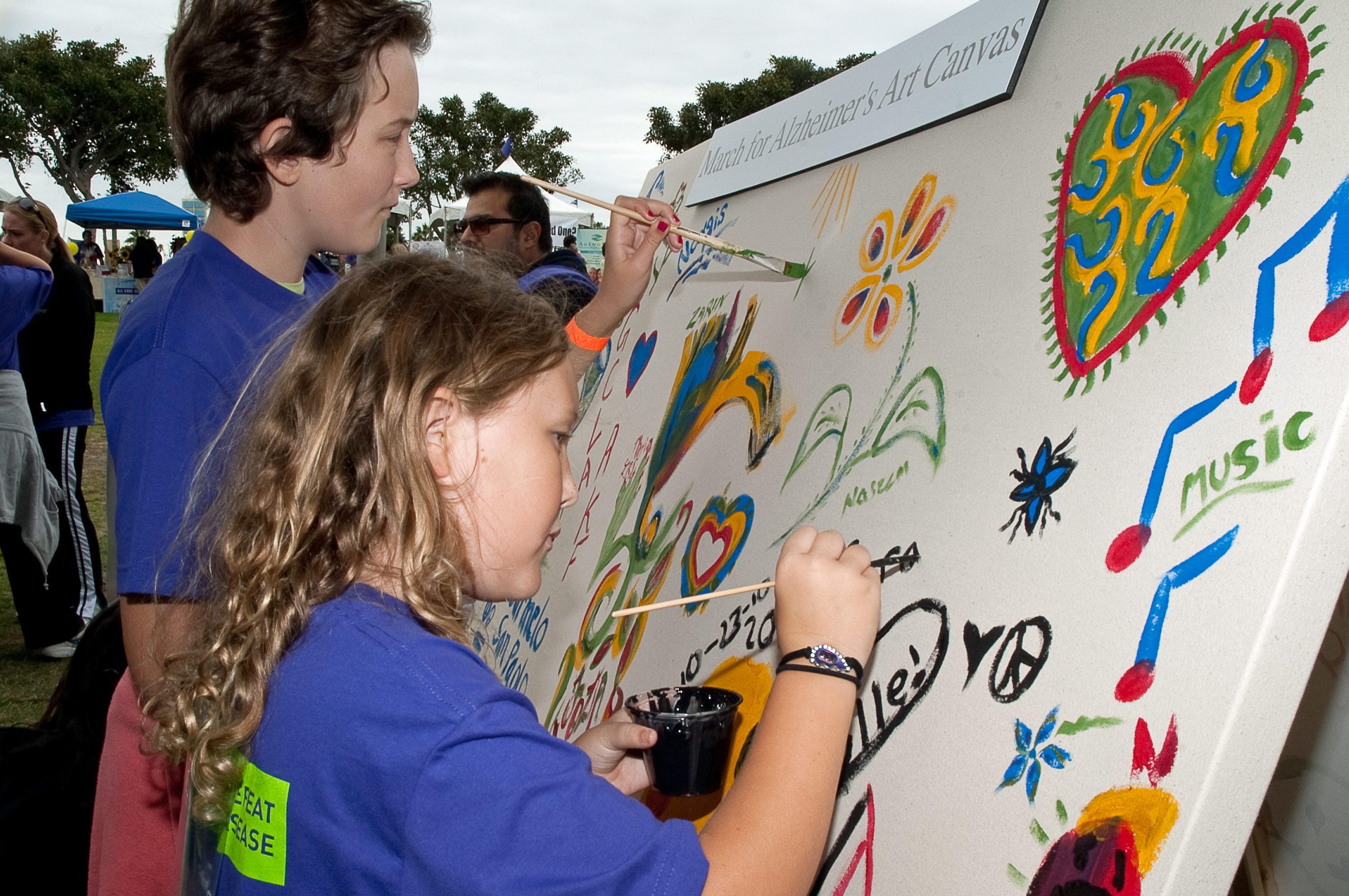 A pair of youth sign the “March for Alzheimer's Art Canvas” at the Ismaili community booth of Maria Shriver's March on Alzheimer's held at Long Beach, California in October 2010. Photo: Shams Soomar