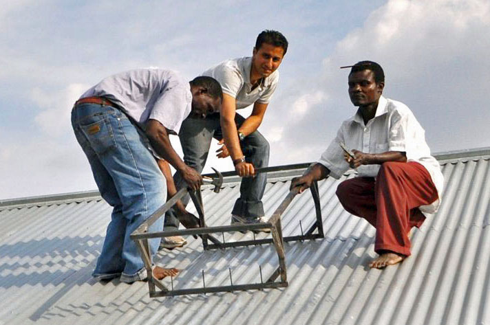 Mawji working with local villagers to install the support structure for a solar panel on top of the roof of the village community centre. Photo: Courtesy of Naeem Mawji