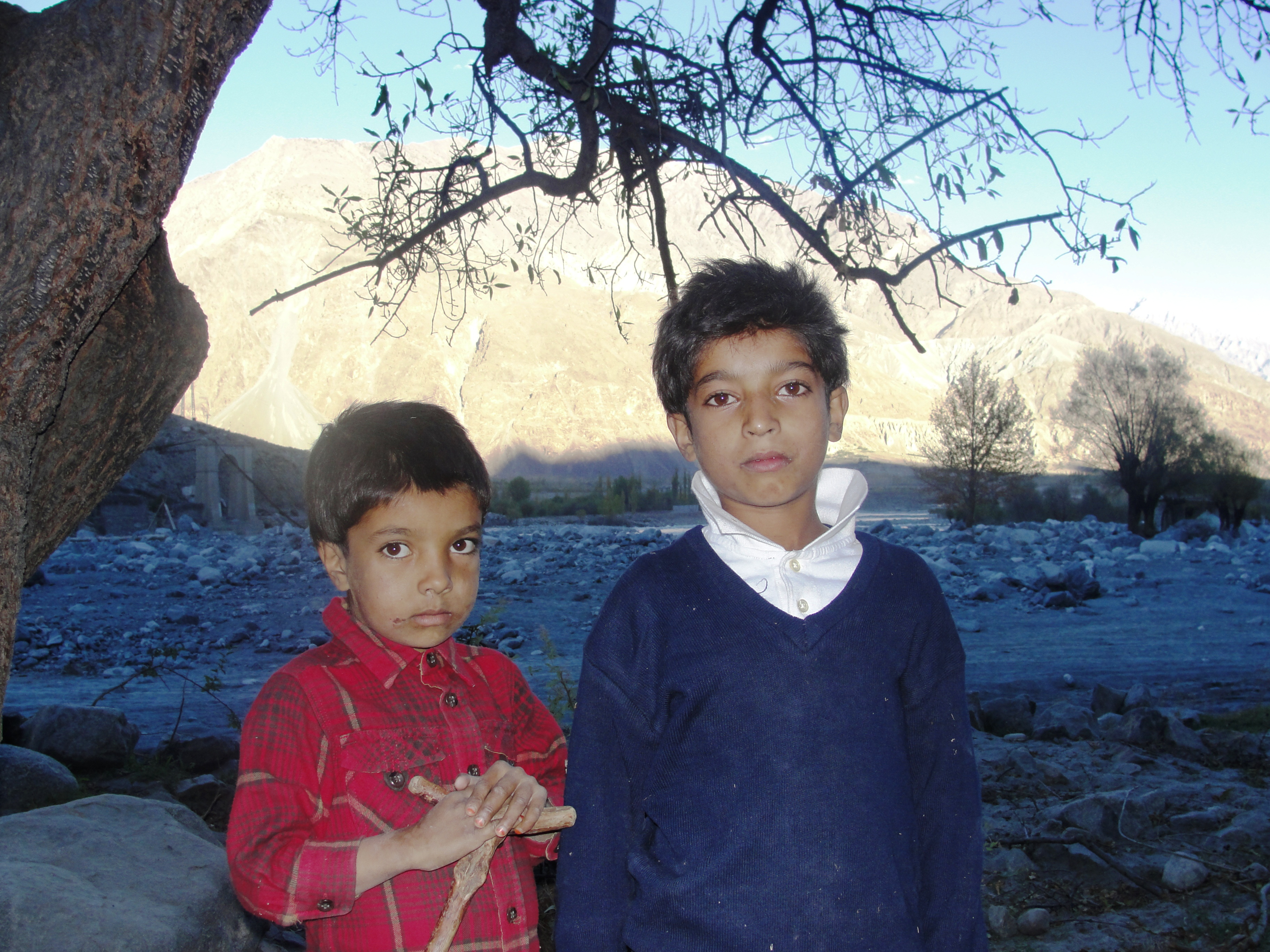 Mashroof, 7 and his 12-year-old brother stand in front of their leveled house in the Hayem village of Punial. Lower parts of Hayem were flooded by the swollen Shandur River, displacing dozens of households and filling the village land with boulders and mud. Photo: Courtesy of FOCUS