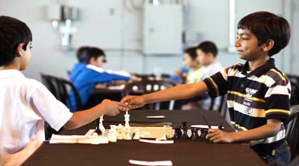 Danial shakes hands with an opponent during a friendly chess competition. Photo: Michael Goulding, Orange County Register