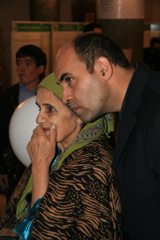 Husnibonu Mamadhasanova, a 73-year-old Ismaili, originally from Badakhshan, watches a film presented at one of the exhibition booths with her son.  Photo: AKDN/Michael Romanyuk  